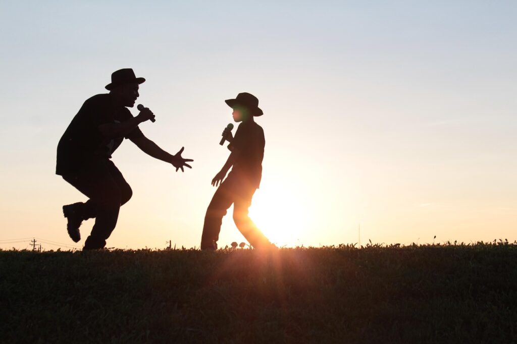 Music for happiness - Man and boy singing in nature